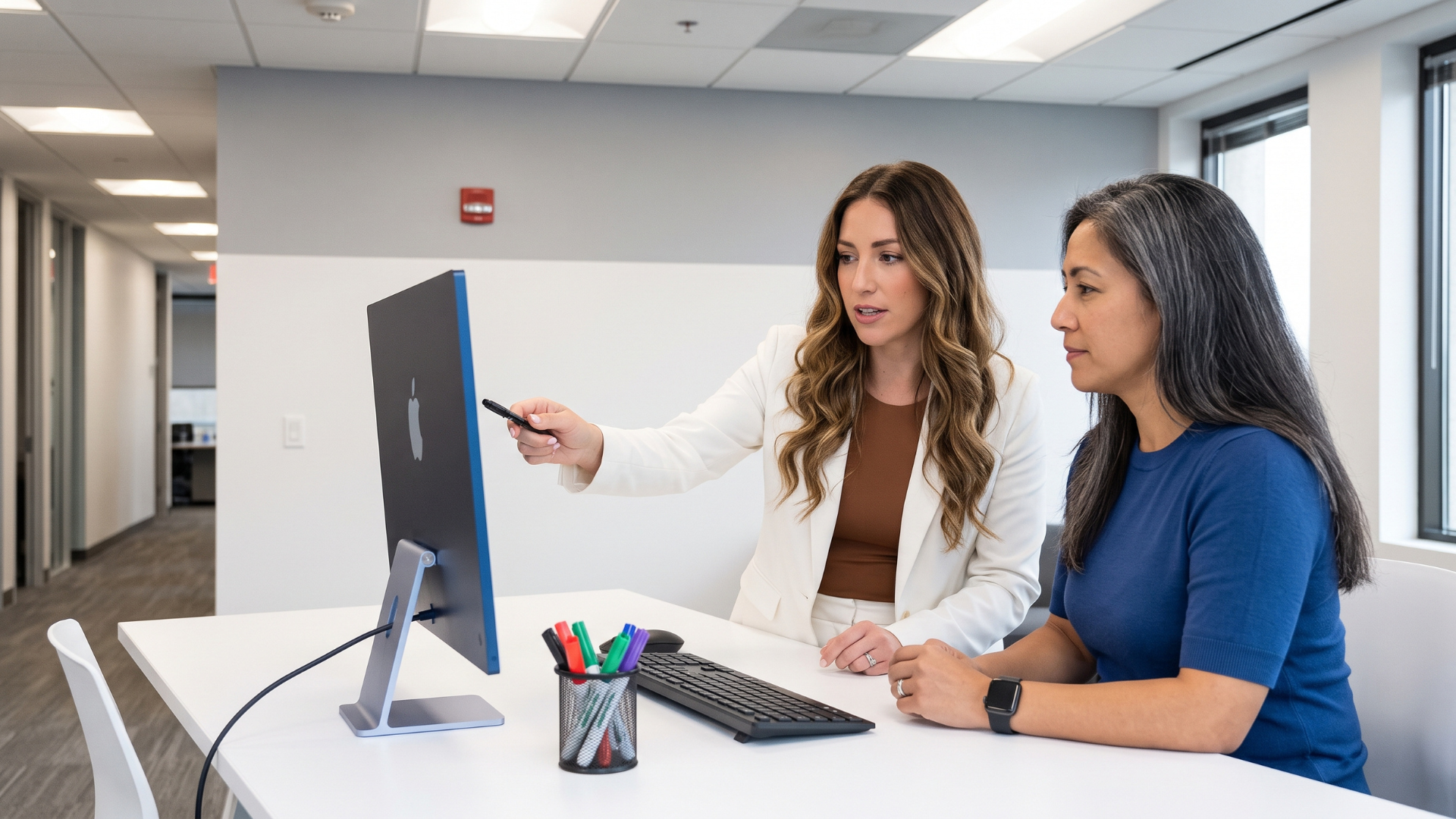 Two colleagues reviewing a course on a desktop screen together in a bright office